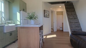 Une cuisine moderne dotée d’un îlot central, d’un coin repas avec un banc et d’un escalier menant à une salle de bain.
