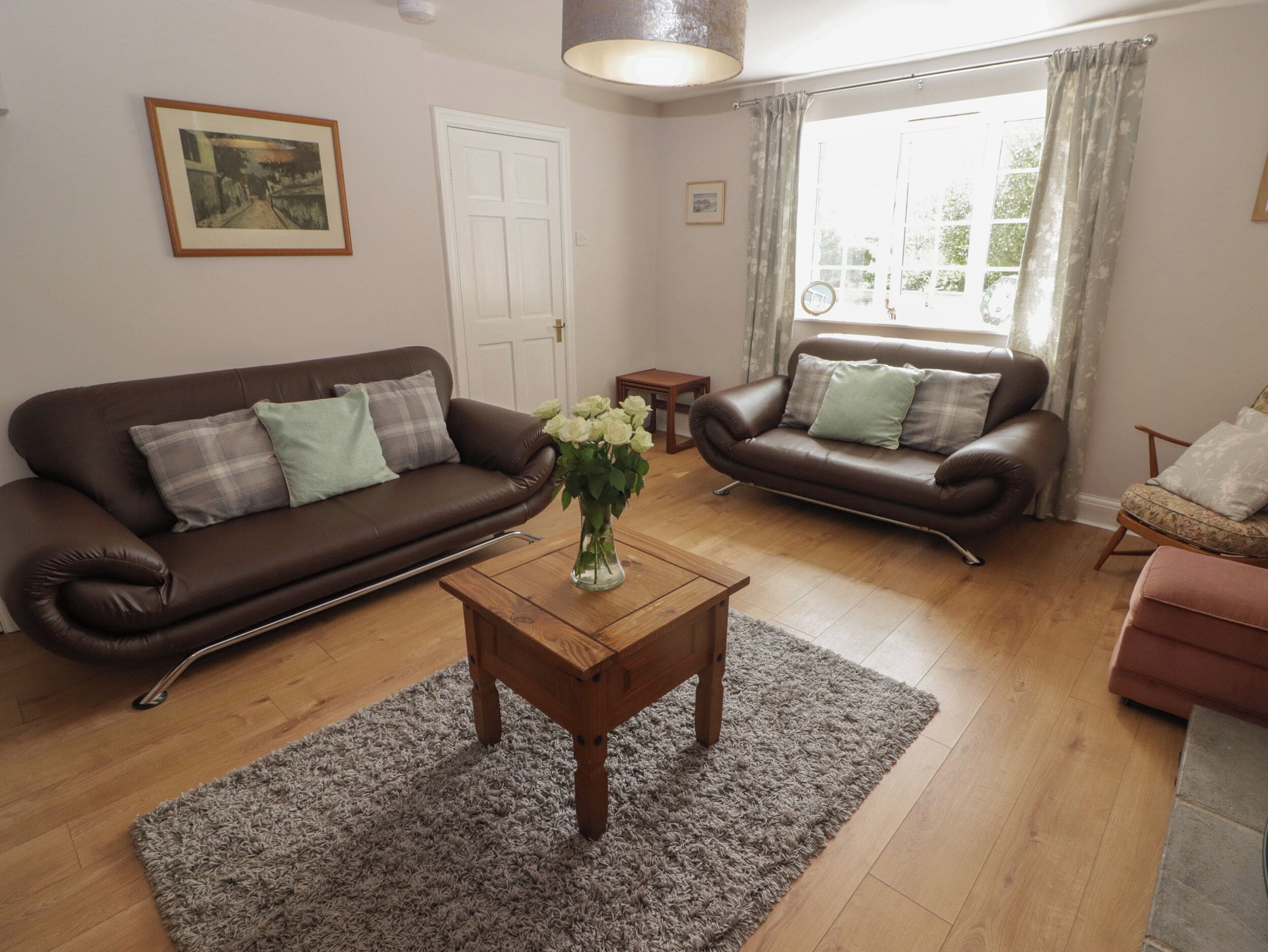 A living room with two brown leather sofas, a wooden coffee table, and a grey rug.