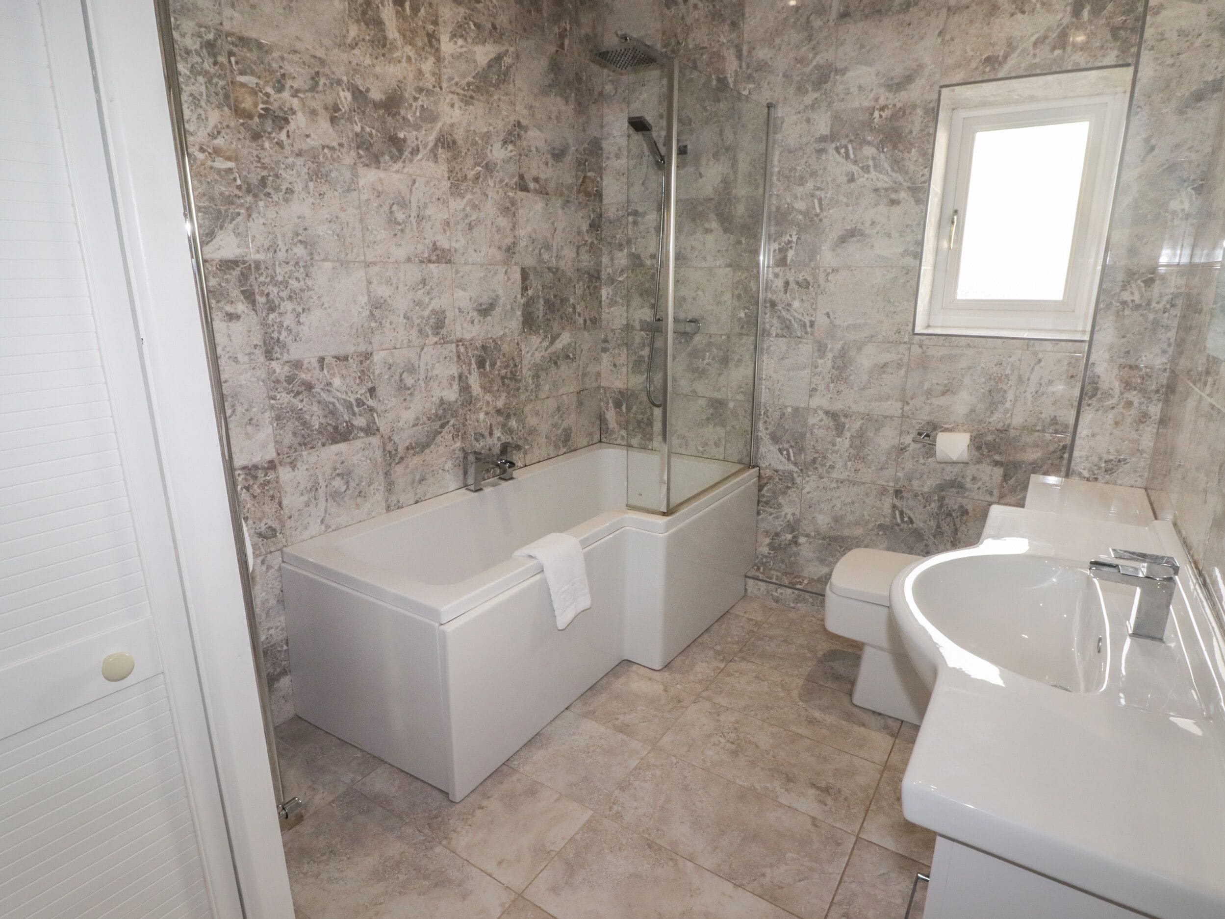 A bathroom with a glass-enclosed shower, a standalone bathtub, and a toilet.