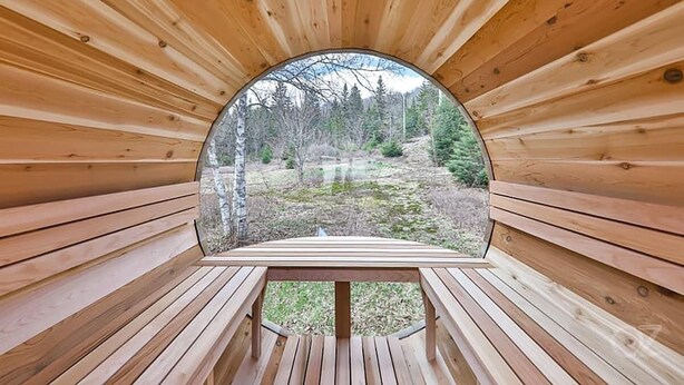 A wooden interior with a circular window offering a view of a forested area. - Sainte-Lucie Luxury, Chalet with Hot Tub, River & Sauna! (Sainte-Lucie-des-Laurentides)