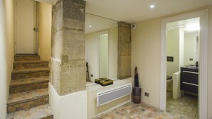 A staircase with a stone pillar, a white console table, and a mirror. - Peaceful appartement in the heart of Le Marais  (Paris)
