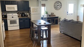 Una cocina amplia con armarios oscuros, una isla central con taburetes, microondas, refrigerador y un ventanal grande.