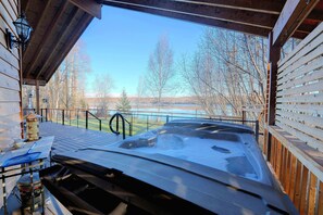 Un bain à remous avec une terrasse en bois et une vue sur un lac et des arbres.