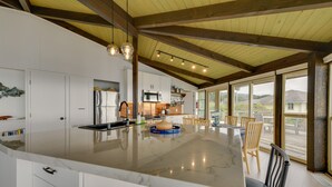 Una cocina amplia con una isla grande, armarios blancos y techo de madera.