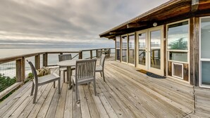 Una terraza de madera con una mesa y sillas, con vista a un cuerpo de agua.