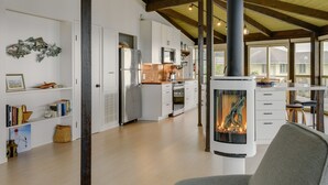 Una cocina moderna con armarios blancos, una isla central y un estufa de leña.