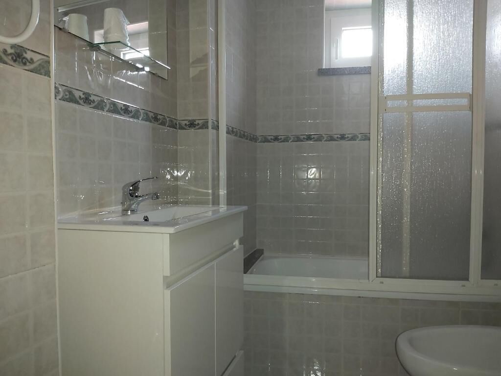 A bathroom with a sink, mirror, and shower area.