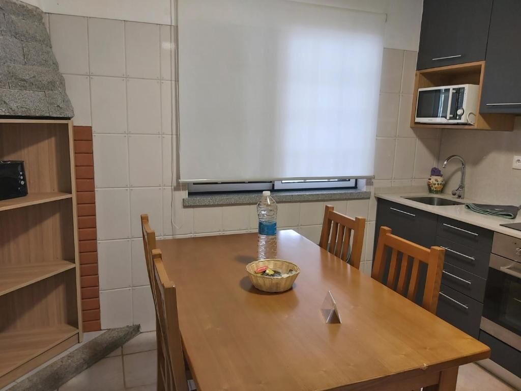 A kitchen with a wooden table, chairs, a microwave, and a window with a view.