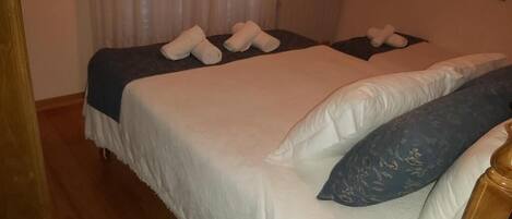 A hotel room with two beds, each with neatly folded towels and a blue patterned pillow.
