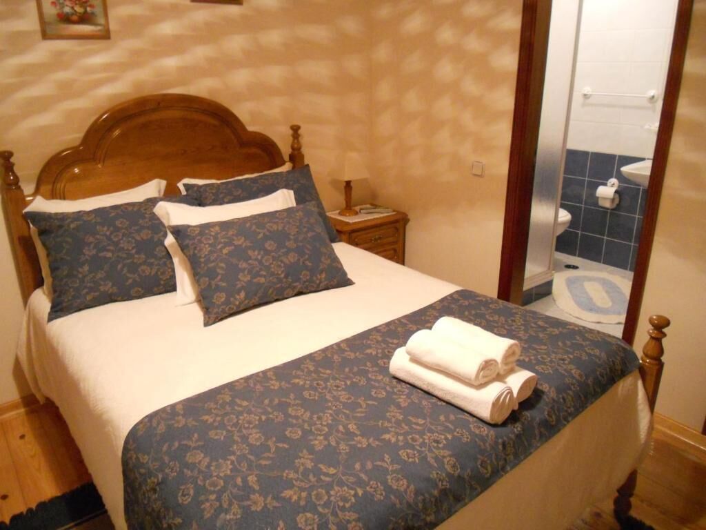 A neatly made bed with a floral bedspread, a wooden headboard, and two pillows.