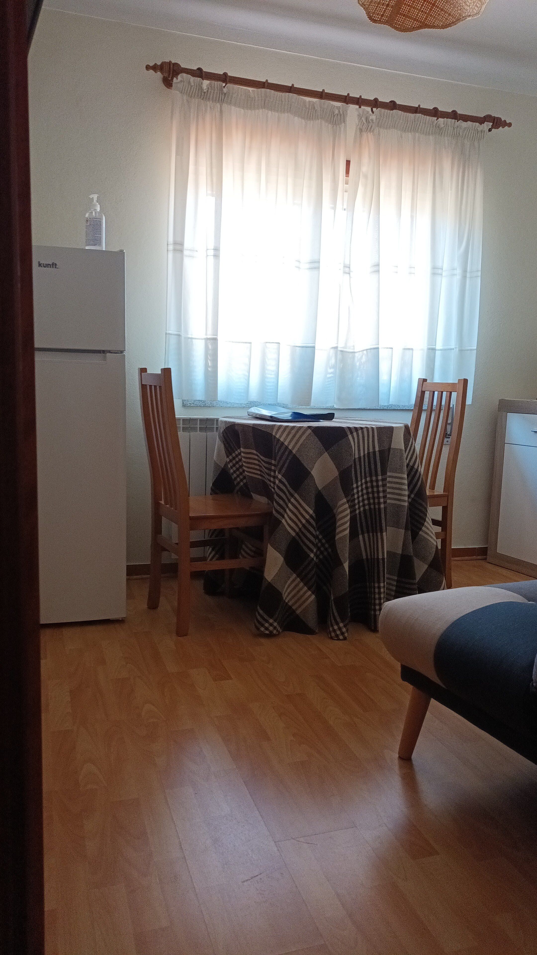 Une petite pièce agréable, avec une table en bois, des chaises, un lit et un coin cuisine.