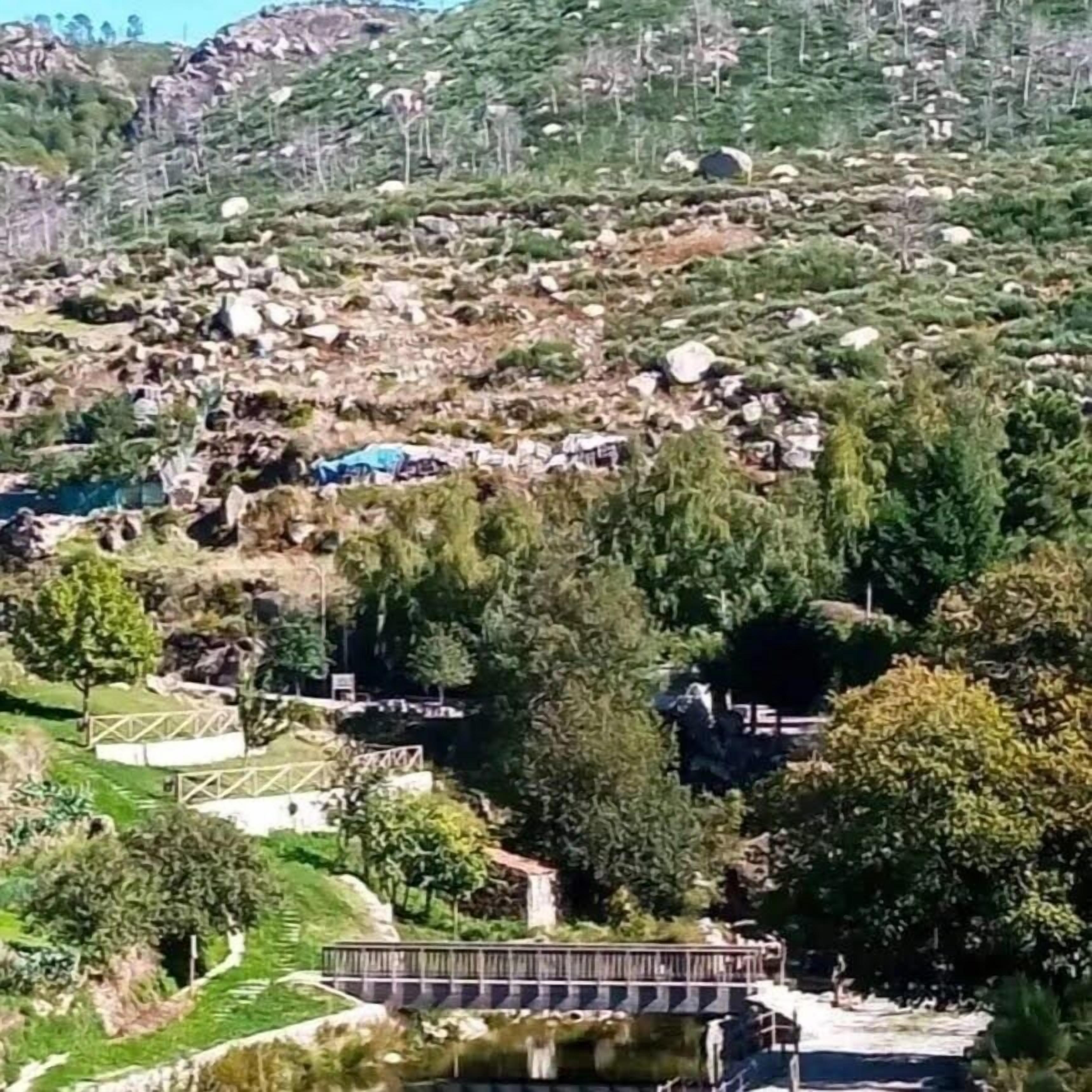 Paisatge de muntanya amb un petit pont i una bassa.