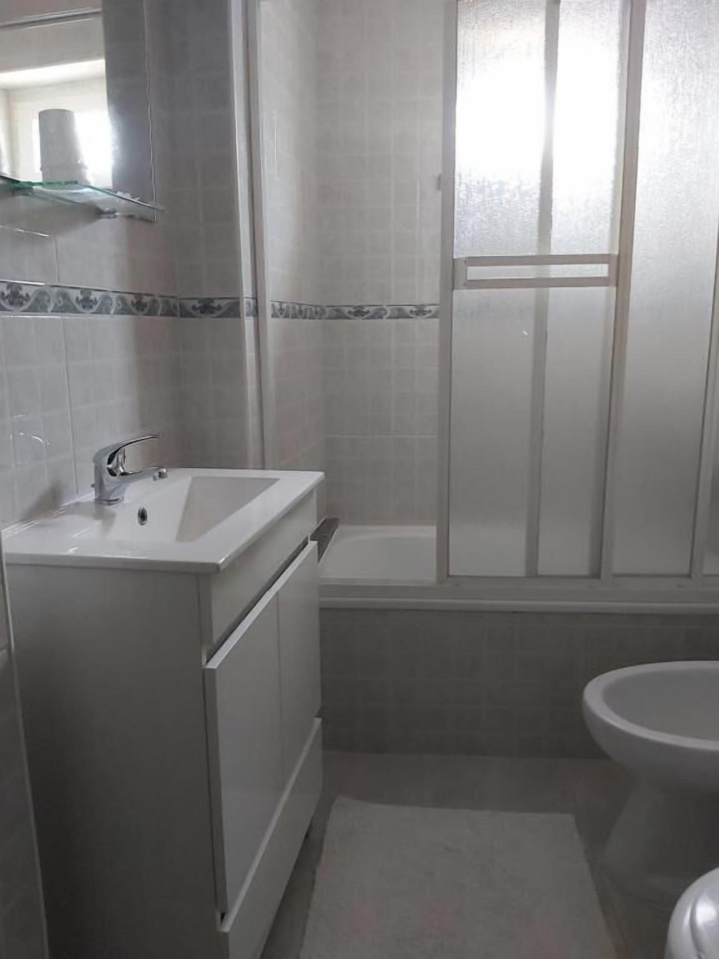 A bathroom with a white sink, a bathtub, and a toilet.