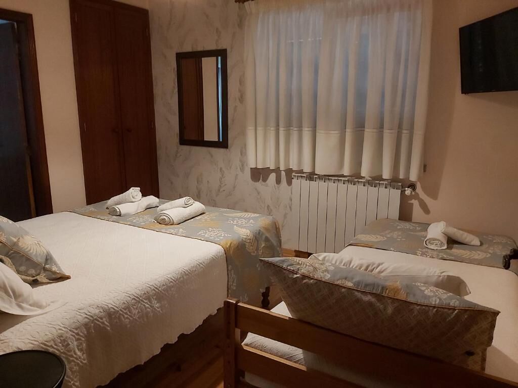 Ένα δωμάτιο ξενοδοχείου με δύο κρεβάτια, ένα ξύλινο προσκέφαλο, ένα καλοριφέρ και έναν καθρέφτη στον τοίχο.