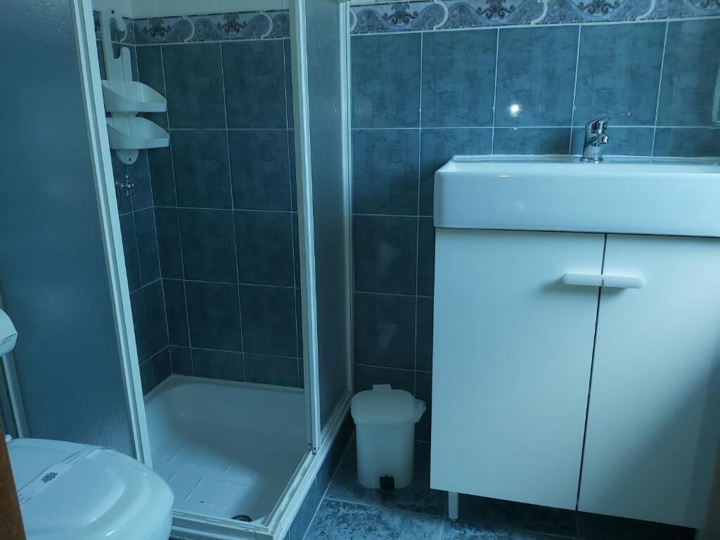 A bathroom with a shower, toilet, sink, and cabinet.