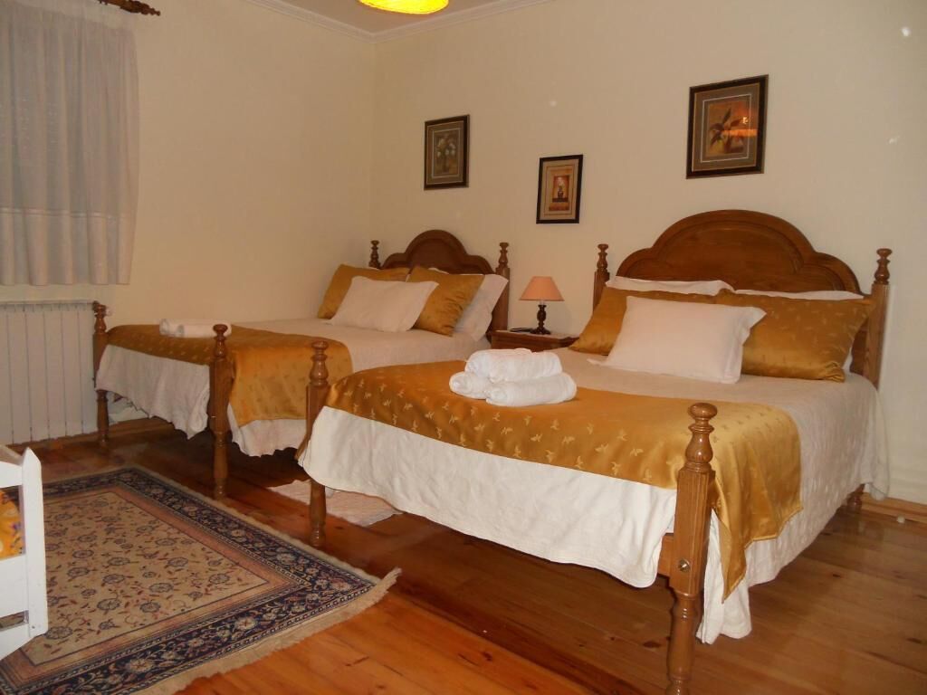Una habitación de hotel con dos camas de madera, una mesita de noche con una lámpara y una alfombra estampada.