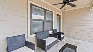 Un patio techado con muebles de mimbre y un ventilador de techo.