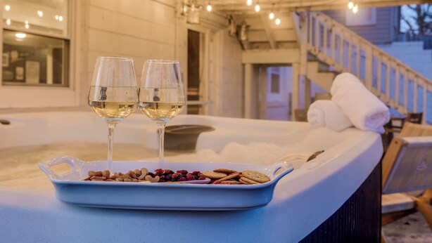 A hot tub with two glasses of white wine and a dish of snacks. - 3 Mins to ND. Hot Tub, Game Room, Sleeps 16, Fire Pit (South Bend)