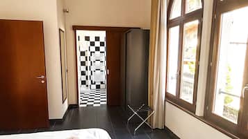 A hotel room with a bed, a checkered door, and large windows.