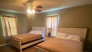Habitación de hotel con dos camas individuales, un ventilador de techo y una mesita de noche con lámpara.