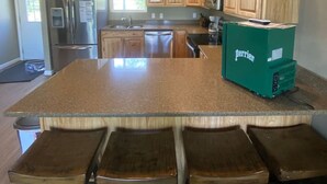 Una cocina con encimera de granito, armarios de madera, electrodomésticos de acero inoxidable y un refrigerador Perrier verde.