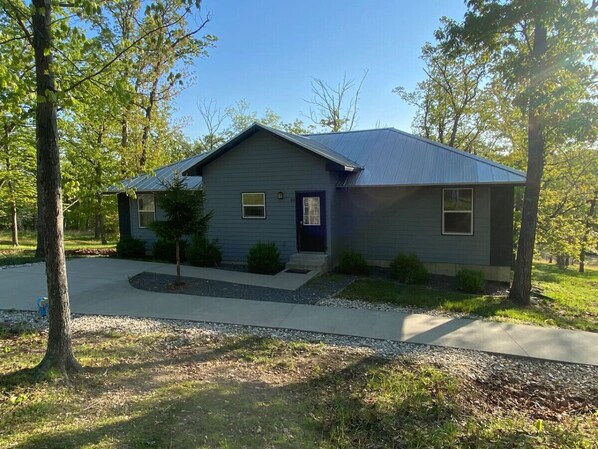 A single-story house with a dark blue exterior, a front porch, and a small front yard.