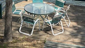 A deck with a round table and four chairs, overlooking a body of water. - Honeysuckle-bachelor/bachelorette parties welcome! (Lake Ozark)