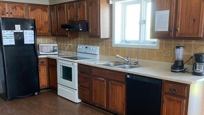 A kitchen with wooden cabinets, a refrigerator, a microwave, an oven, a dishwasher, a sink, and a window. - Honeysuckle-bachelor/bachelorette parties welcome! (Lake Ozark)