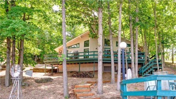 A wooden deck with steps leading to a building surrounded by trees. - Honeysuckle-bachelor/bachelorette parties welcome! (Lake Ozark)