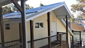 Ein zweistöckiges Haus mit überdachter Veranda und kleiner Terrasse.