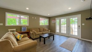 A spacious living room with a beige sofa, a coffee table, and a television on a stand.