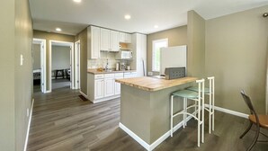 A modern kitchen with white cabinets, a wooden island, and bar stools.
