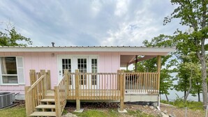 A pink building with a wooden deck and stairs leading to a door.