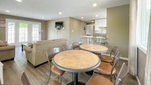 A modern interior with two round tables, a sofa, and a kitchen area.