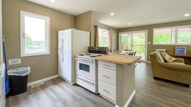 A compact kitchen with a refrigerator, stove, and wooden countertop.