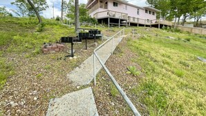 Un bâtiment rose doté d’un balcon, entouré d’une zone herbeuse et accessible par un chemin en béton.