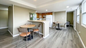 Une cuisine moderne dotée d’un îlot central, d’un coin repas avec des chaises et d’une petite table.