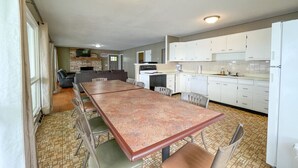 Una cocina amplia con armarios blancos, una mesa de comedor con sillas y una sala de estar independiente con un sofá y una televisión.