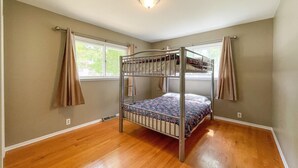 Una habitación con literas, suelo de madera y una ventana con cortinas.