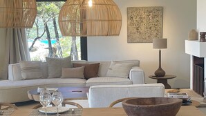 Una sala moderna con una mesa de comedor de madera, sillas de mimbre, un sofá y dos lámparas colgantes de mimbre.