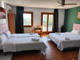 Habitación de hotel con dos camas, una mesa de comedor y vistas al exterior.