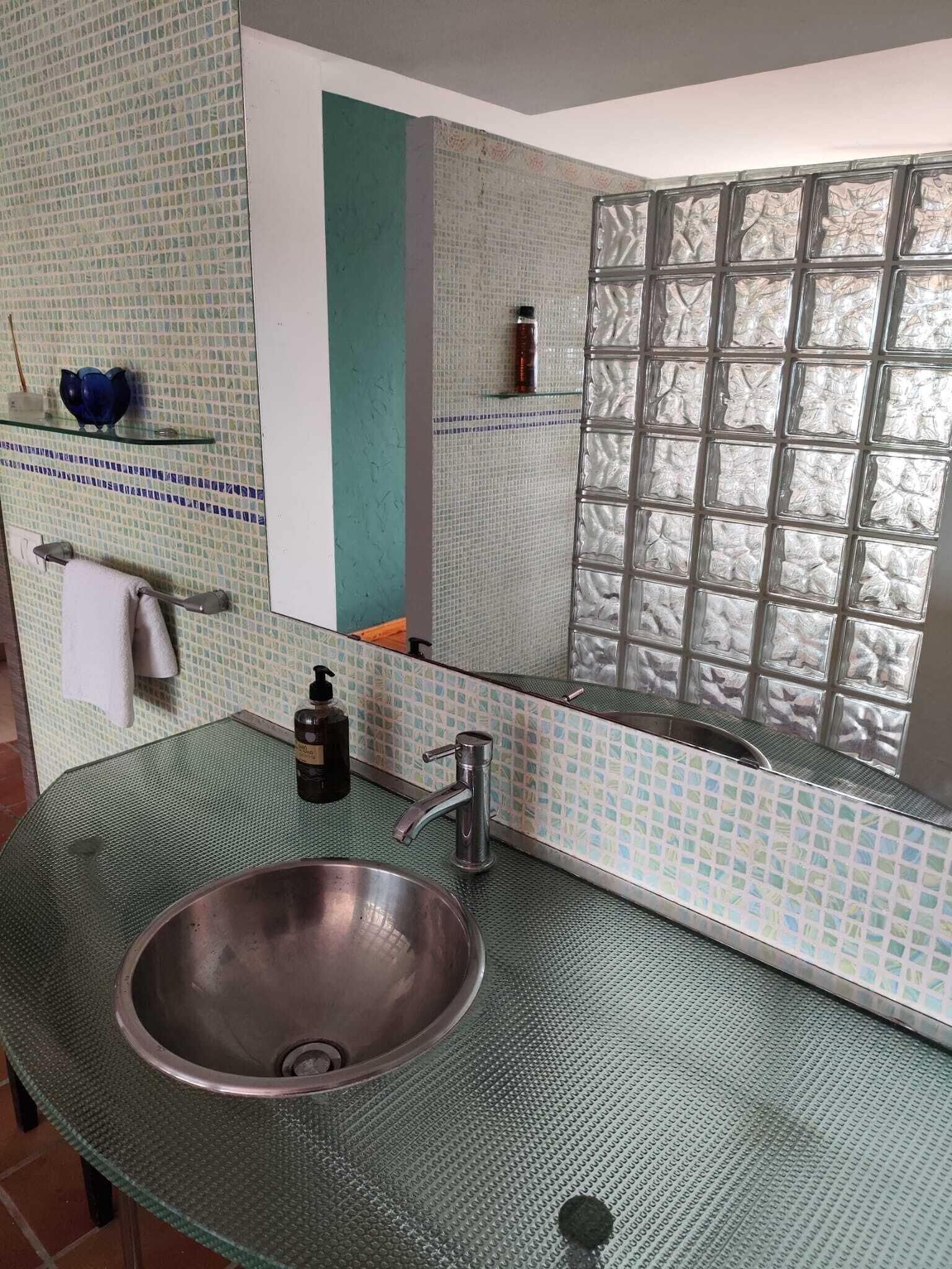 Un baño con un espejo grande, un lavamanos con grifo y un salpicadero de azulejos.