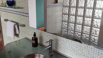 Un baño con un espejo grande, un lavamanos con grifo y un salpicadero de azulejos.