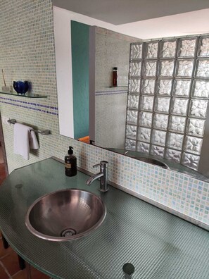 A bathroom with a large mirror, a sink with a faucet, and a tiled backsplash.