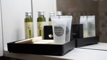 Ein Badezimmer-Waschtisch mit einer schwarzen Ablage, auf der sich eine Shampooflasche, eine Duschgel-Flasche und mehrere Seifenflaschen befinden.