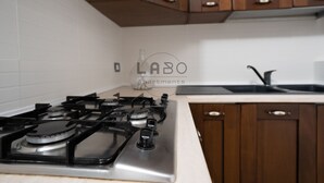 A kitchen with a gas stove, wooden cabinets, and a sink. - Ammos Guest House (Tropea)