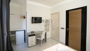 A modern bedroom with a bed, a desk, a chair, a television, and a wardrobe. - Ammos Guest House (Tropea)