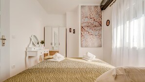 Camera d'albergo con un letto grande, una scrivania con uno specchio, un armadio e un grande quadro astratto appeso alla parete.