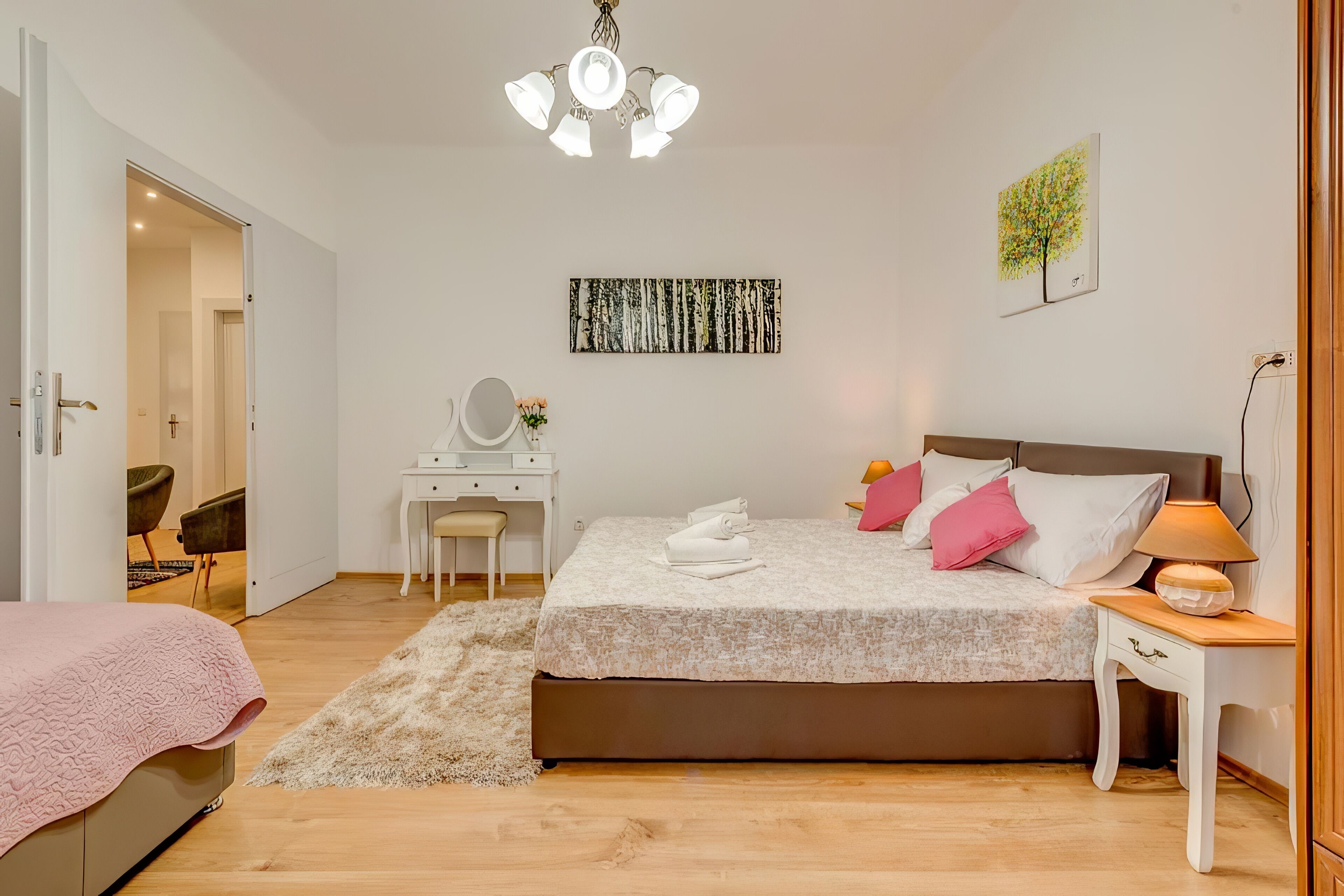 A bedroom with a bed, bedside table, lamp, and artwork on the wall.