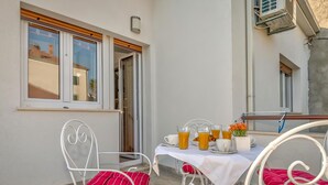 Un balcone con un tavolo apparecchiato per la colazione, con succo d'arancia e pasticcini.